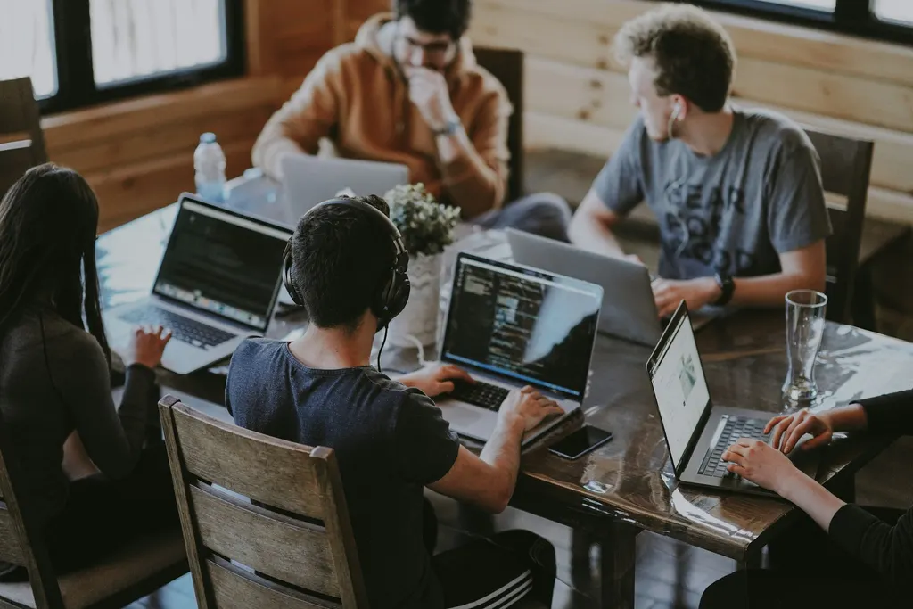 Vier Personen arbeiten an Laptops an einem gemeinsamen Tisch